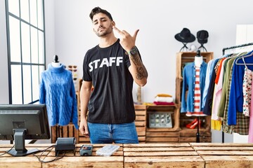 Young hispanic man working at retail boutique showing middle finger, impolite and rude fuck off expression - obrazy, fototapety, plakaty