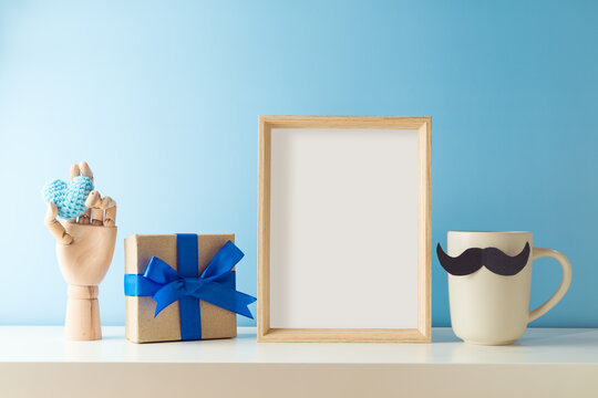 Picture frame mock up with coffee cup and gift box on white table. Father's day greeting card concept
