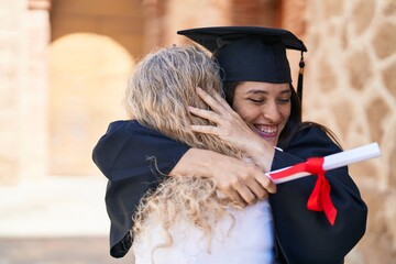 Two women mother and graduated daughter hugging each other at campus university