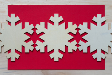 wooden snowflake ornaments on red paper and wood