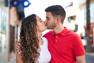 Young hispanic couple smiling confident hugging each other and kissing at street