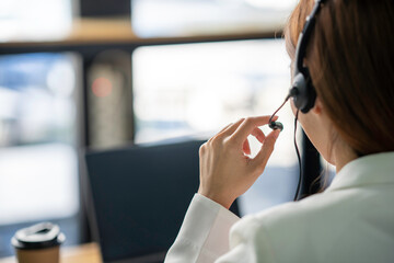 Friendly female helpline operator with headphones in call center
