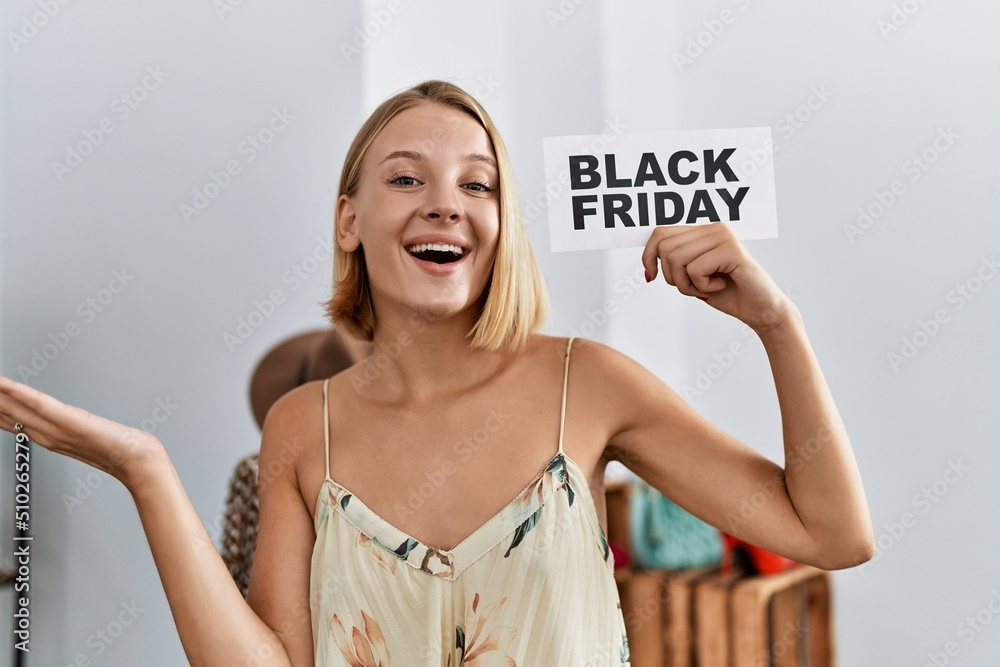 Sticker Young caucasian woman holding black friday banner at retail shop celebrating achievement with happy smile and winner expression with raised hand