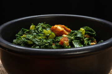 Cabbage with diced bacon served in a clay bowl on a rustic wooden table