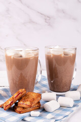 Two mugs with hot cocoa drink and marshmallow, butter cookies on a blue cloth napkin with a place for text. Vertical photo.