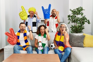 Group of senior people supporting soccer team at home annoyed and frustrated shouting with anger, yelling crazy with anger and hand raised