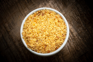Farofa served in a clay bowl on a rustic wooden table