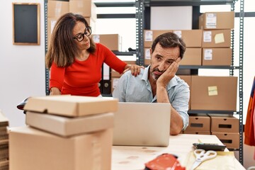 Middle age man and woman business partners stressed working at storehouse