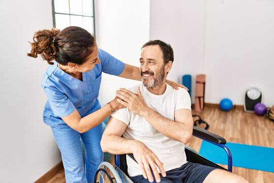 Middle age man and woman smiling confident having physiotherapy session at physiotherapy clinic