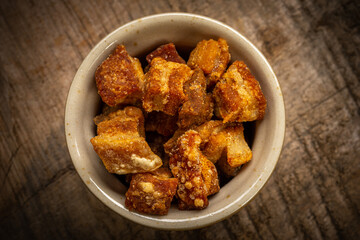 Fried greaves served in a clay bowl on a rustic wooden table