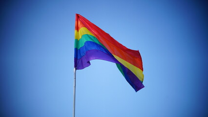 Rainbow gay pride flag against blue sky
