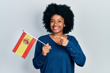 Young african american woman holding spain flag smiling happy pointing with hand and finger