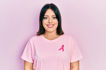 Young hispanic woman wearing pink cancer ribbon on t shirt with a happy and cool smile on face. lucky person.