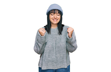 Young hispanic woman wearing cute wool cap excited for success with arms raised and eyes closed celebrating victory smiling. winner concept.