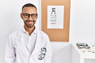 Fototapeta na wymiar African american optician man standing by eyesight test winking looking at the camera with sexy expression, cheerful and happy face.
