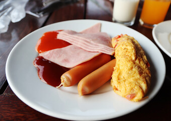 close up American breakfast, sausage, omelette, bacon on a white plate