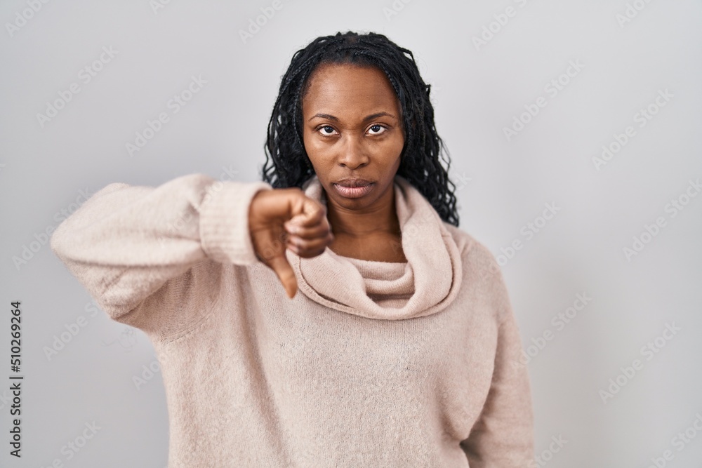 Sticker African woman standing over white background looking unhappy and angry showing rejection and negative with thumbs down gesture. bad expression.