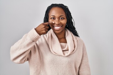 African woman standing over white background pointing with hand finger to face and nose, smiling cheerful. beauty concept