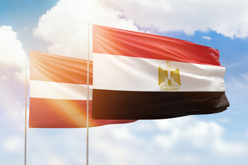 Sunny blue sky and flags of egypt and latvia