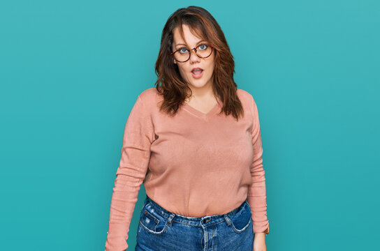 Young plus size woman wearing casual clothes and glasses in shock face, looking skeptical and sarcastic, surprised with open mouth