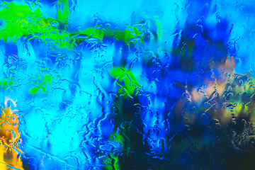 natural abstract texture background obtained from melting ice on car glass and blurred nature behind the glass, illuminated by sunlight