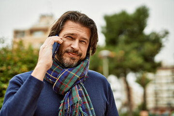 Middle age handsome man speaking on the phone outdoors at the park