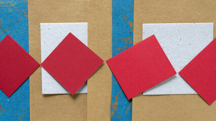 red paper tiles on white, gold, and blue paper with texture