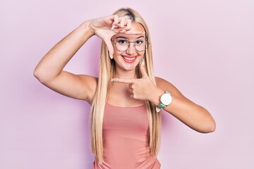 Young blonde girl wearing casual clothes smiling making frame with hands and fingers with happy face. creativity and photography concept.