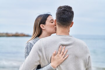 Man and woman couple hugging each other on back view at seaside