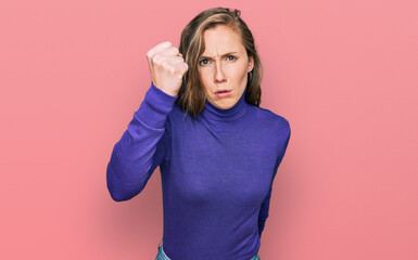 Young blonde woman wearing casual clothes angry and mad raising fist frustrated and furious while shouting with anger. rage and aggressive concept.