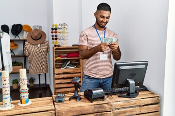 Young arab man holding dollars working at clothing store