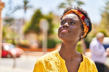 Young african american woman smiling confident looking to the sky at street