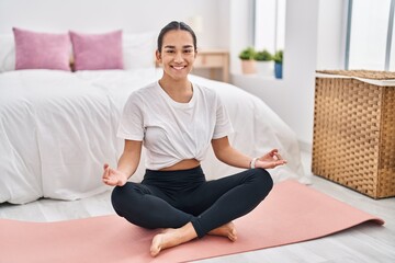 Fototapeta na wymiar Young hispanic woman smiling confident training yoga at bedroom