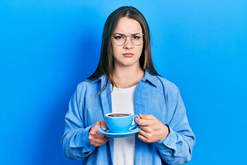Young hispanic girl drinking a cup of coffee clueless and confused expression. doubt concept.
