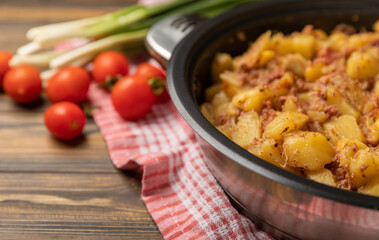 Braised pork with potatoes and onions on a brown wood. Composition with vegetables. Place to copy. Place for text. Fried potato recipe.