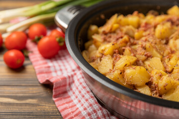 Braised pork with potatoes and onions on a brown wood. Composition with vegetables. Place to copy. Place for text. Fried potato recipe.