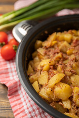 Braised pork with potatoes and onions on a brown wood. Composition with vegetables. Place to copy. Place for text. Fried potato recipe.