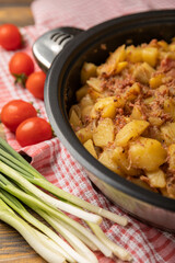 Braised pork with potatoes and onions on a brown wood. Composition with vegetables. Place to copy. Place for text. Fried potato recipe.