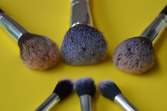 Professional cosmetic makeup brushes of different sizes on a yellow background for applying powder, shadows and blush and other cosmetic products