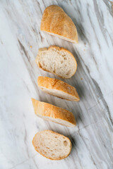 Fresh sliced baguette bread on marble table. Healthy eating breakfast.