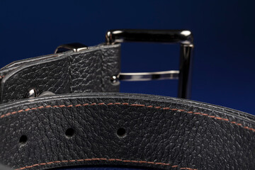Black leather belt on a dark blue background.