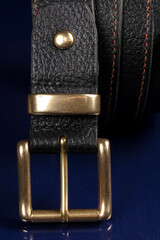 Black leather belt on a dark blue background.