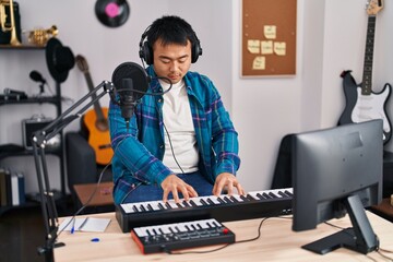 Young chinese man singer singing song playing piano keyboard at music studio