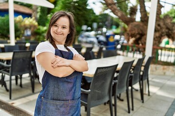 Young down syndrome woman smiling confident wearing apron at coffee shop terrace