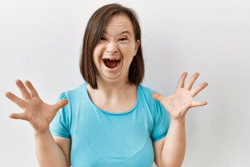 Young down syndrome woman standing over isolated background celebrating mad and crazy for success...