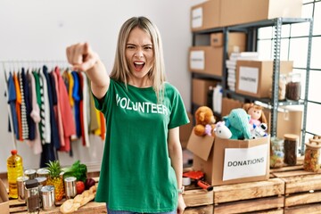 Asian young woman wearing volunteer t shirt at donations stand pointing displeased and frustrated to the camera, angry and furious with you