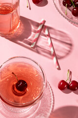 Festive flat lay with cherries drinks and a gift box, all in pink color