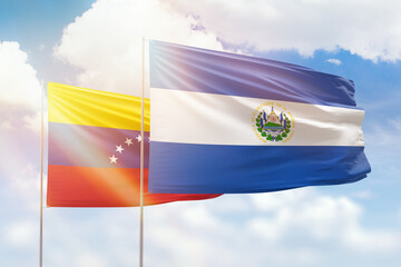 Sunny blue sky and flags of el salvador and venezuela