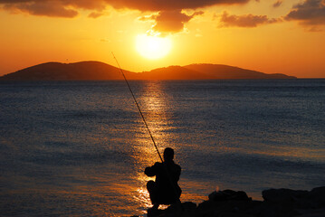 fishing on the beach at sunset