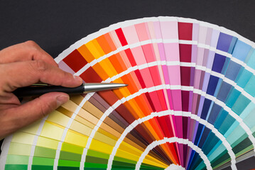 Female hand chooses color in palette swatches. Rainbow colors catalog isolated on black